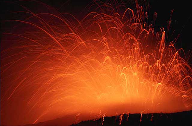 Lava exploding out of volcano at night.